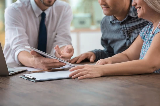 Réunion d'affaires en intérieur avec trois professionnels assis autour d'une table de travail
