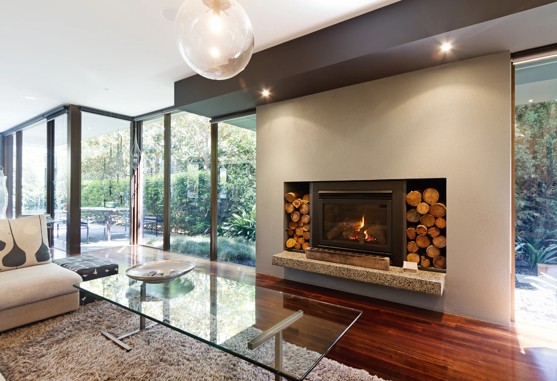 Intérieur moderne avec cheminée à foyer fermé en fonctionnement, flammes visibles à travers vitre panoramique