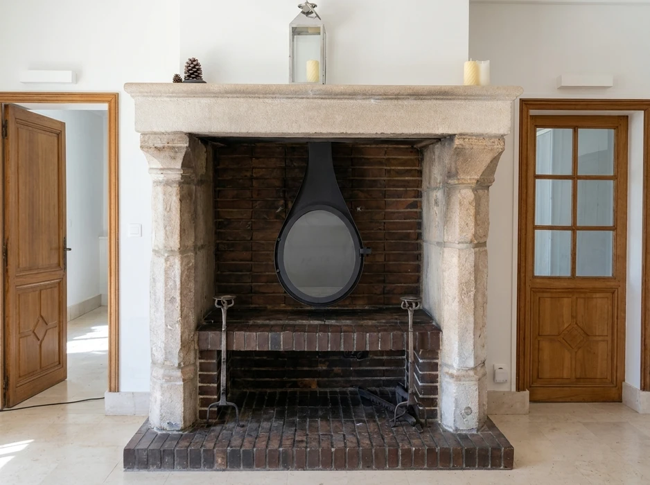 Intérieur rustique avec cheminée encadrée d'un manteau en pierre calcaire sculptée, ornements floraux et pilastres